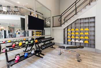a spacious fitness center with treadmills and weights with a staircase in the background